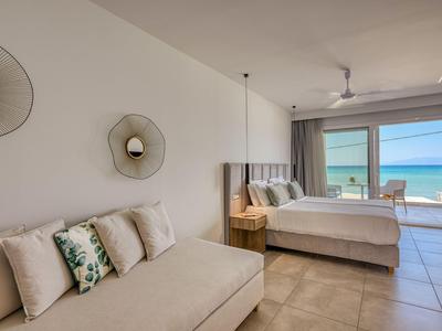 Modernes Hotelzimmer mit Doppelbett, einer gemütlichen Couch und Meerblick durch große Fenster.