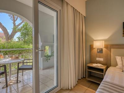 Hotelzimmer mit Blick auf möblierten Balkon und grüne Umgebung.