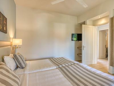 Hell eingerichtetes Hotelzimmer mit zwei Betten und einem Fernseher an der Wand.