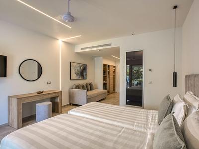 Modern eingerichtetes Hotelzimmer mit Doppelbett, Sofa und Schreibtisch in neutralen Farben.