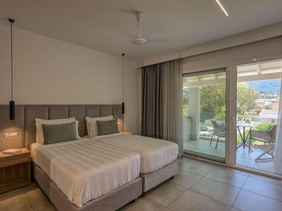 Modernes Hotelzimmer mit zwei Einzelbetten und Balkon mit Bergblick.