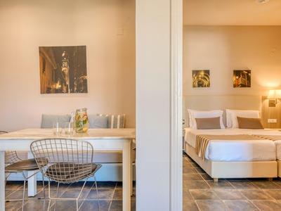 Modernes Hotelzimmer mit Essbereich und Doppelbett, heller Wandfarbe und stilvollen Möbeln.
