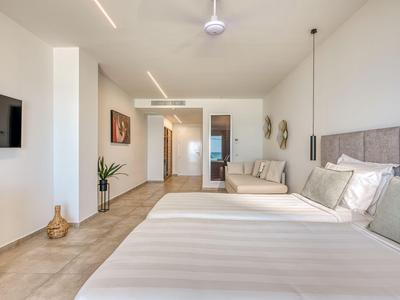 Helles Hotelzimmer mit großem Bett, Sofa, moderner Einrichtung und neutralen Farben.