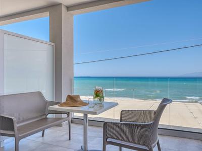 Balkon mit zwei Stühlen und Tisch, Blick auf Meer und klaren Himmel an der Küste.