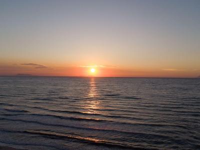 Sonnenuntergang über ruhigem Meer mit sanften Wellen und klarem Himmel.