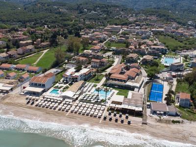 Ein weitläufiges Strandhotel mit Pools, Liegestühlen und direktem Zugang zum Meer in einer grünen Küstenstadt.