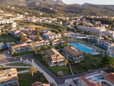 Luftaufnahme eines weitläufigen Hotels mit mehreren Gebäuden, Pools und Bergen im Hintergrund.