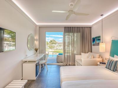Modernes Hotelzimmer mit großem Bett, Terrasse und Blick auf das Meer bei Tageslicht.