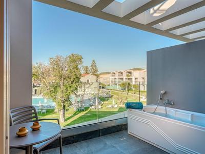 Balkon mit moderner Badewanne, Stühlen und Blick auf Grünflächen und Gebäude.
