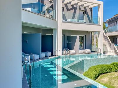 Modernes Hotel mit Pool und Glasgeländer unter blauem Himmel.