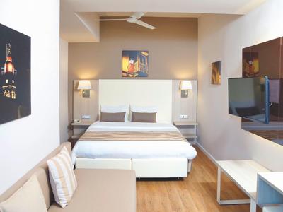 Helles, modernes Schlafzimmer mit Doppelbett, Sitzbank, Holzboden und Wandbildern.