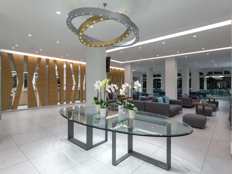 Moderner Eingangsbereich mit großem Glas-Tisch, Designer-Leuchter und hellen, weißen Bodenfliesen.