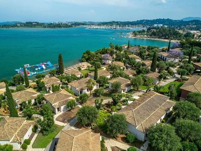 Blick auf ein Resort mit roten Ziegeldächern an einer blauen Küste mit grüner Vegetation.