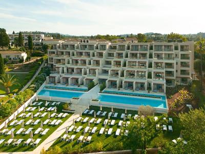 Modernes Hotel mit zwei großen Außenpools und Liegen in gepflegtem Garten.