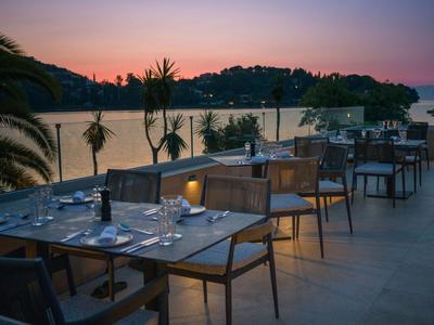 Terrasse eines Hotels mit gedeckten Tischen und Blick auf einen Fluss bei Sonnenuntergang.