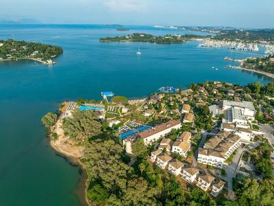 Luftaufnahme einer Küstenanlage mit Hotels, umgeben von blauem Meer und grünem Wald.
