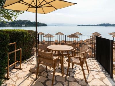 Terrasse mit Holzmöbeln und Sonnenschirm mit Blick auf einen See und Inseln.