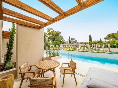 Poolbereich mit Holzdach, runden Tisch mit Stühlen und Blick auf Liegestühle und Gärten.
