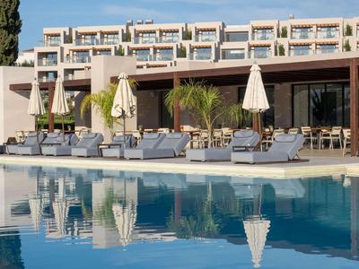 Moderner Hotelpoolbereich mit Liegestühlen, Sonnenschirmen und klar reflektierendem Wasser.