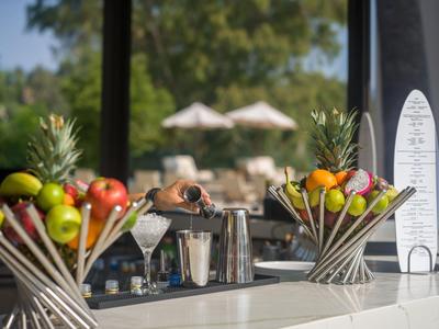 Ein Barkeeper bereitet einen Cocktail an einer modernen Bar mit Obst und Shaker vor.
