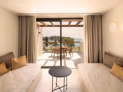 Helles Hotelzimmer mit zwei Einzelbetten und Balkon mit Meerblick.