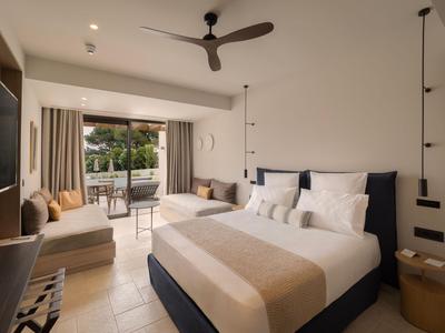Modernes Hotelzimmer mit Doppelbett, Deckenventilator und Balkon mit Sitzbereich.