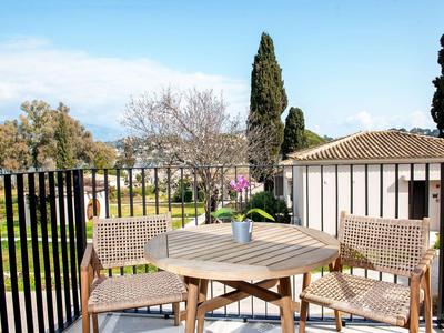 Balkon mit Holztisch und Stühlen mit Ausblick auf Garten und Gebäude.