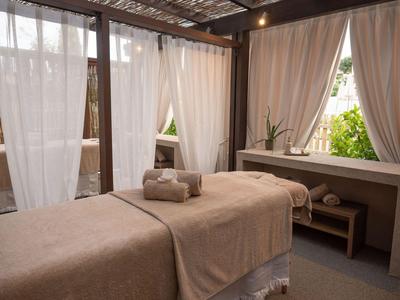 Ein ruhiger Wellnessbereich mit Massagetisch, beigen Tüchern und sanftem Tageslicht durch weiße Vorhänge.