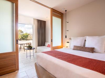 Modern eingerichtetes Hotelzimmer mit Doppelbett und Zugang zu Balkon
