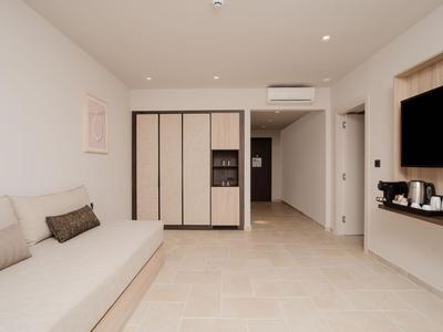 Helles Hotelzimmer mit Sofa, Fernseher, Klimaanlage und Kleiderschrank.