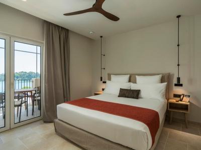 Modernes Hotelzimmer mit Doppelbett, Terrassentür und Blick auf See