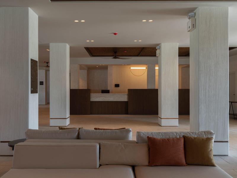 Moderne Lobby mit beigen Sofas, weißen Säulen und dunklem Empfangstresen.