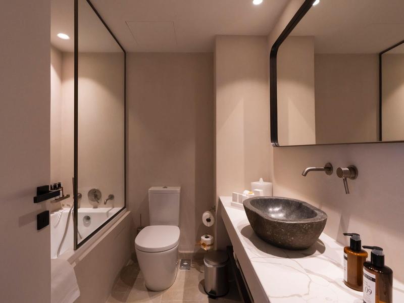 Kleine, moderne Toilette mit weißem WC, schwarzem Waschbecken und großen Spiegeln.