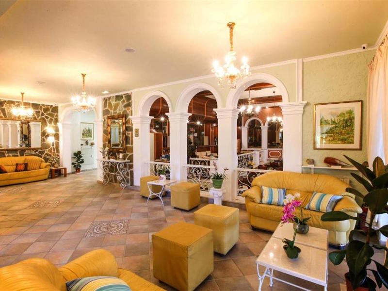 Lichte hotel lounge met gele fauteuils, kleine tafels en een gespiegeld gedeelte.