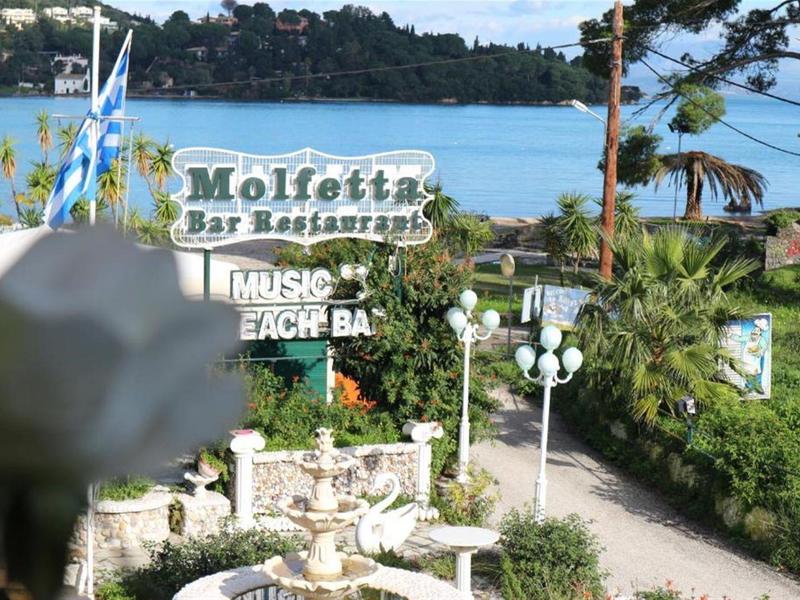 Uitzicht op een pad omgeven door palmbomen met een bord voor Molietta Bar & Restaurant aan het strand.