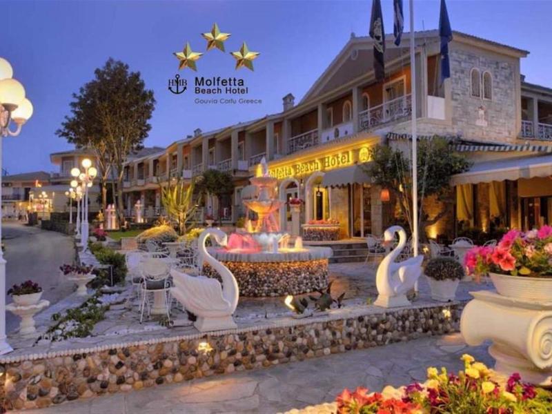 Avondzicht op het verlichte Meliá Hotel aan het water met een decoratief buitengebied en bloemen.