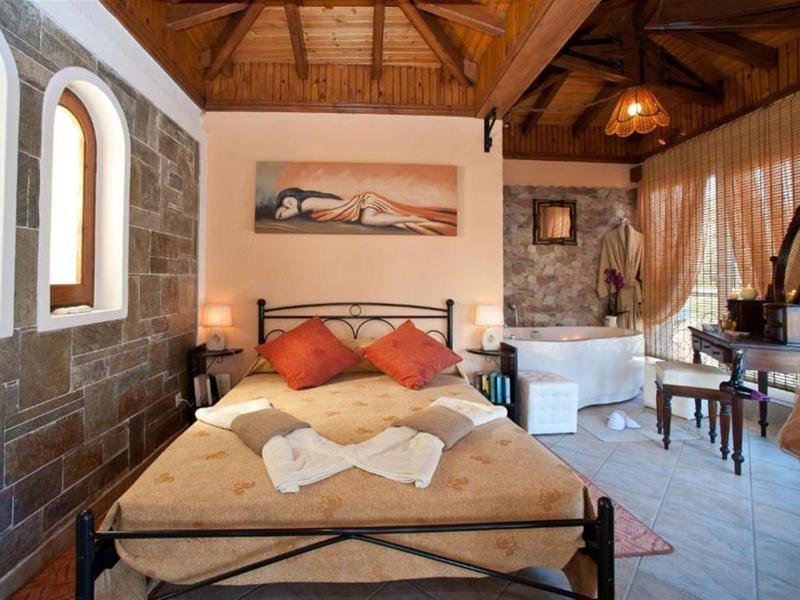 Gezellige hotelkamer met houten balkenplafond, stenen muren en tweepersoonsbed met decoratieve kussens.