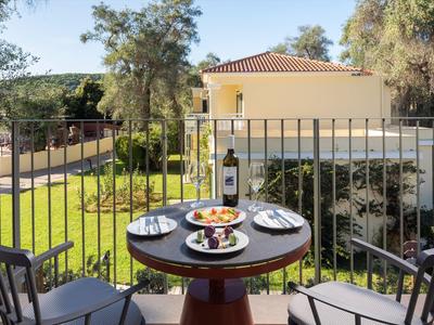 Balkon mit runden Tisch und zwei Stühlen, Blick auf grünen Garten und Wohnhaus.