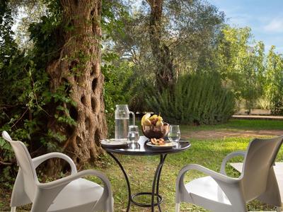 Kleiner runder Tisch mit Snacks und Getränken, umgeben von zwei weißen Stühlen im Garten.