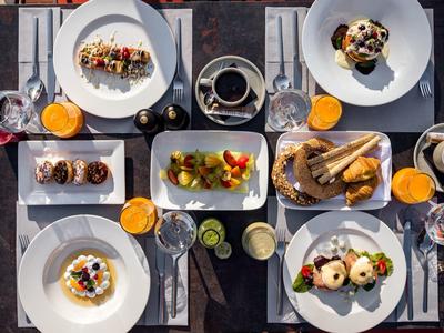 Tisch mit verschiedenen Frühstücksgerichten, Getränken und Besteck in einem Hotel.