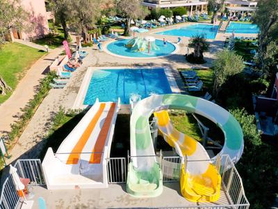 Blick auf einen Außenpool mit drei Wasserrutschen in einem Hotelgarten.