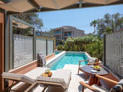 Terrasse mit Pool, Liegestühlen und Tisch mit Getränken in einem Hotel