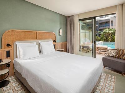 Modernes Hotelzimmer mit Doppelbett und Blick auf einen Pool durch die Glasschiebetür.