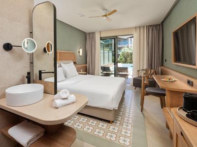 Modern eingerichtetes Hotelzimmer mit Doppelbett, Arbeitsbereich und Balkon mit Blick ins Grüne.