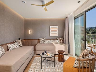 Modern eingerichtetes Wohnzimmer mit großen Fenstern und Blick auf eine Terrasse und Natur