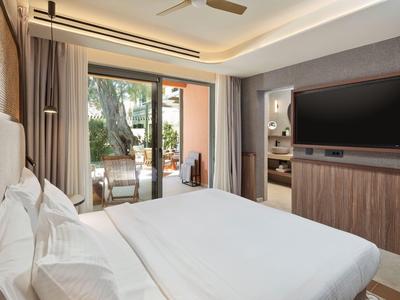 Modernes Hotelzimmer mit Doppelbett, TV und Zugang zu Terrasse mit Gartenblick.