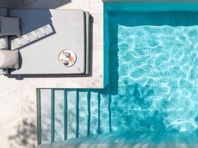 Vogelperspektive auf einen Pool mit angrenzender Liegefläche und Schatten