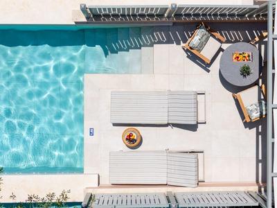 Vogelperspektive eines Pools mit zwei Liegestühlen und einem kleinen Tisch im modernen Außenbereich.
