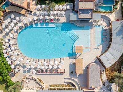 Aerial view of a hotel pool with sun loungers and white umbrellas outdoors.