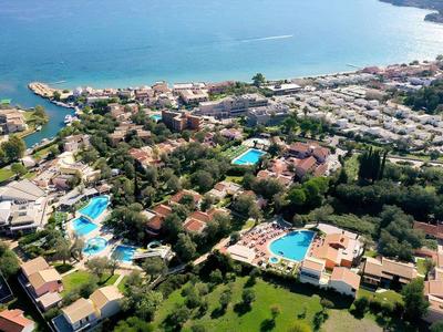 Luftaufnahme eines Ferienresorts mit mehreren Pools, Gebäuden und Blick auf das Meer.